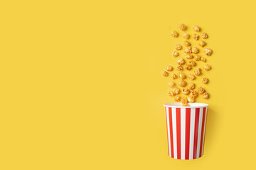 Popcorn bucket, cinema treat, movie snack, caramel delight, yellow background, copy space
