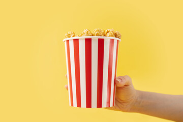 Hand with popcorn box, movie night, entertainment at home, classic film treat