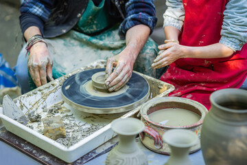 Craftsman, potter teaches the child to make ceramic pot on pottery wheel craft, craft work concept