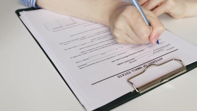 Affidavit of small estate, hand fills out a document, real estate sale, agent signature, property transaction.