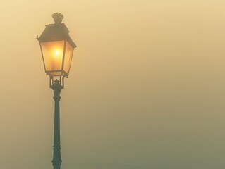 Illustrate a vintage lamppost standing in the midst of a foggy morning, casting a warm, inviting glow against the hazy backdrop