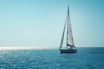 Obraz premium A sailboat competing in a regatta on the vast open ocean, navigating through light wind.