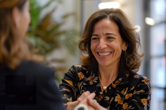 Two women, one with brown hair named Patricia Botn, smiling and shaking hands in a business setting.