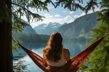 A woman rests in nature near a pond. Girl in a hammock against the background of mountains. Concept: holiday in the mountains near a lake