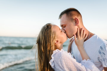 Woman kisses man on sand sea. Closeup face. Female kissing and hugging male stand on beach ocean...