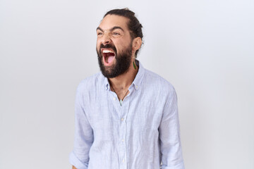 Hispanic man with beard wearing casual shirt angry and mad screaming frustrated and furious,...