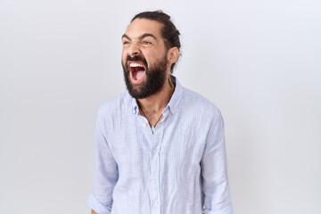 Obraz premium Hispanic man with beard wearing casual shirt angry and mad screaming frustrated and furious, shouting with anger. rage and aggressive concept.