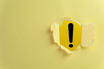 Exclamation Mark Tearing Through Yellow Paper: Highlighting Important Message and Warning Sign in a Striking Visual.