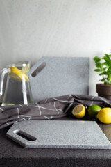 Kitchen setup with gray stone cutting boards, lemons and limes, glass pitcher containing beverage...