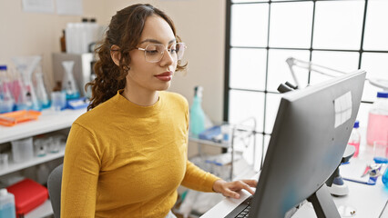 A focused woman works on a computer in a modern lab, portraying technology, healthcare, and professionalism in an indoor setting.