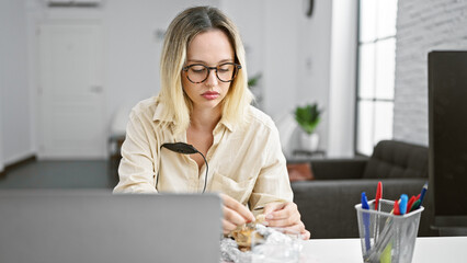Young blonde woman business worker eating sandwich working at the office