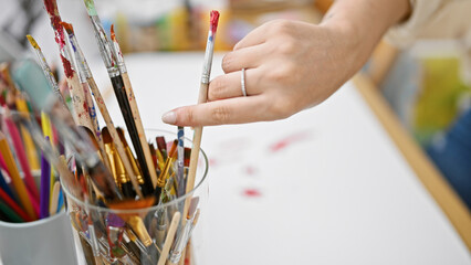Young blonde woman artist holding paintbrush at art studio