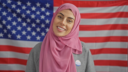 A smiling woman with a hijab proudly displaying an 'i voted today' sticker, with the american flag...