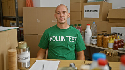 Young hispanic man volunteer sitting on table with serious face at charity center