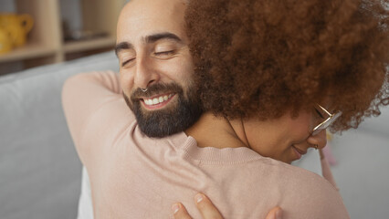 Close-up of a happy interracial couple embracing in a cozy indoor setting, reflecting love and...