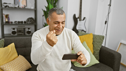 Middle-aged hispanic man playing video game in living room, joyful expression, home interior.