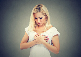 Sick woman with heart attack, pain, holding touching her chest with hands.