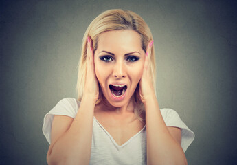 Portrait of a screaming young woman with hands on ears gesture 