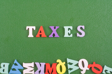 TAXES word on green background composed from colorful abc alphabet block wooden letters, copy space...