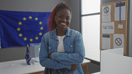 A smiling young woman with arms crossed in a room with european union flags, representing...