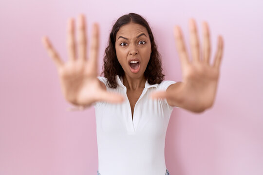 Young hispanic woman wearing casual white t shirt doing stop gesture with hands palms, angry and frustration expression