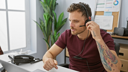 Fototapeta premium A young hispanic man with a beard works in an office, wearing a headset for communication.