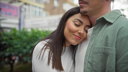 A loving couple embraces on a city street, exuding affection with a serene urban backdrop.