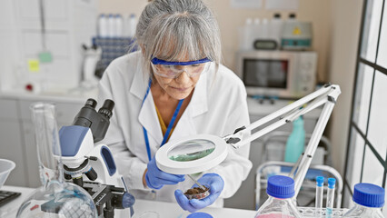 Mature woman scientist examining specimen in laboratory setting, depicting research and healthcare...
