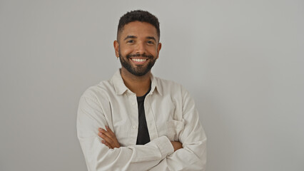 Portrait of a confident young adult black man with arms crossed smiling over isolated white...