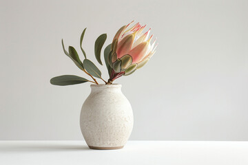 A minimalist arrangement featuring a single blue hydrangea bloom displayed in a modern ceramic vase...