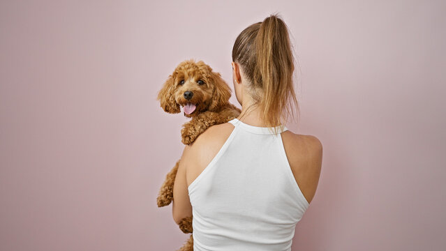 Young caucasian woman with dog hugging backwards over isolated pink background