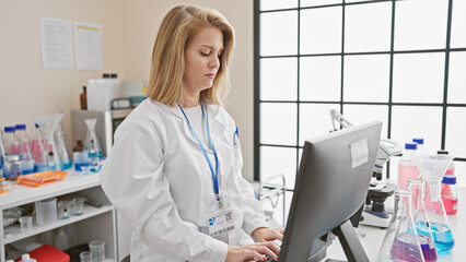 Focused woman scientist using computer in modern laboratory with equipment