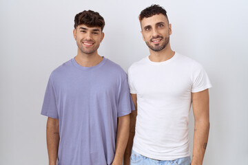 Homosexual gay couple standing over white background with a happy and cool smile on face. lucky...
