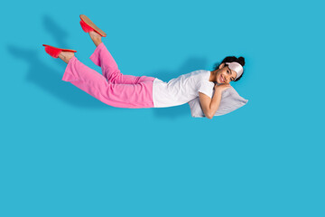 Full body portrait of pretty young woman levitate pillow wear pajama isolated on blue color background