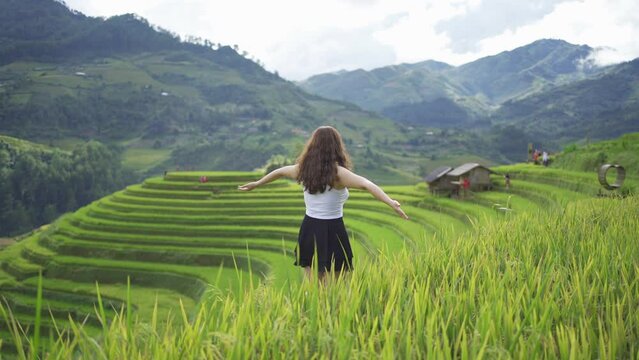 A farmer woman with fresh paddy rice terraces, green agricultural fields in countryside or rural area of Mu Cang Chai, mountain hills valley in Asia, Vietnam. Nature landscape. People lifestyle.