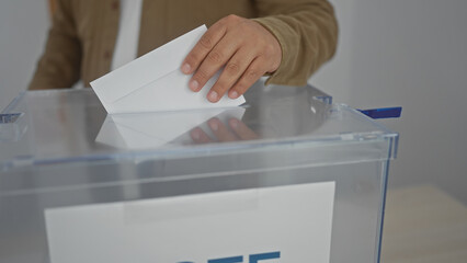 A man casting a ballot at a voting box indoors during an election.