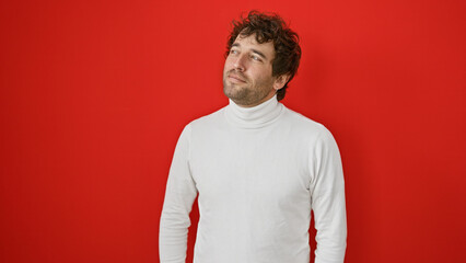 A contemplative hispanic man with a beard poses against a red background, exuding casual elegance.