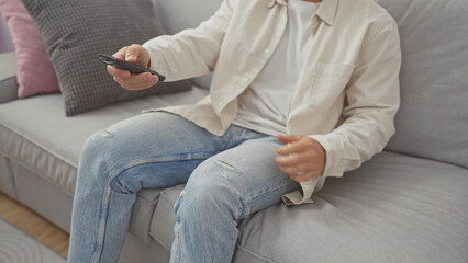 A young man relaxing on a sofa while holding a tv remote in a modern living room