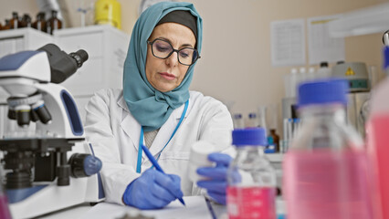 Middle-aged woman in hijab engaged in scientific research at laboratory