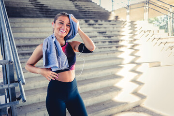 Smiling, tired and woman with towel for sweat after workout, training or exercise. Sports idea, exhausted and sweating female athlete wipe with fabric after exercising, running or cardio.