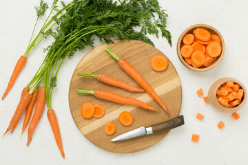 Bunch of fresh carrots with sliced ones on concrete background, top view