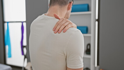 Fototapeta premium Man experiencing shoulder pain in a modern rehabilitation clinic's interior