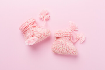 Pink baby booties on color background, top view