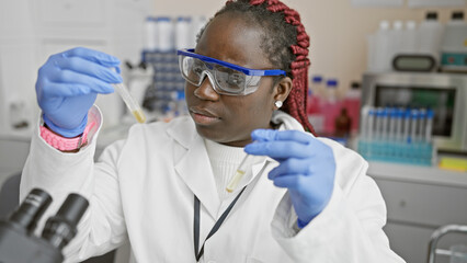 African american woman scientist with braids examining a test tube in a laboratory setting.