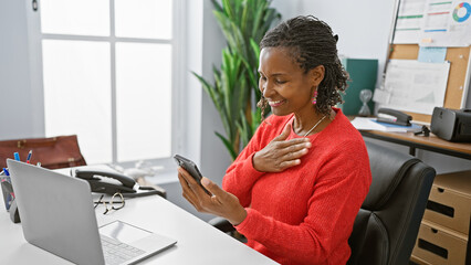 African american woman smiling while using smartphone in office, highlighting productivity and...