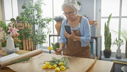 Elderly woman using smartphone in flower shop surrounded by plants and floral arrangements
