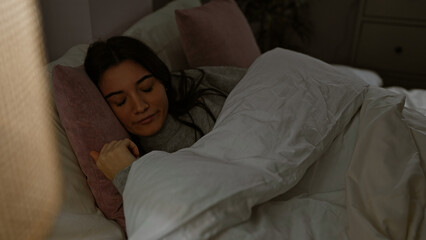 Young hispanic woman sleeping peacefully in a dark bedroom setting at night, showcasing tranquility...