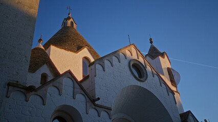 Charming alberobello townscape with iconic white trulli houses bathed in warm sunlight against a...