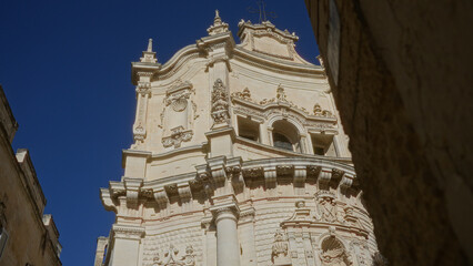 Baroque architecture detail of a historic building captured in lecce, puglia, italy, showcasing ornate stonework under a clear, blue sky in a european town.