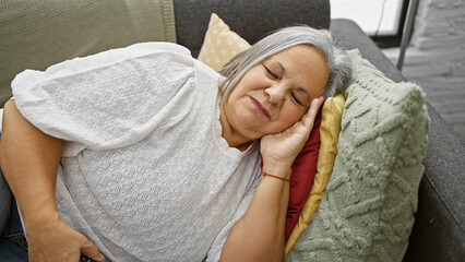 A senior woman peacefully sleeping on a couch at home, hinting at relaxation and comfort.